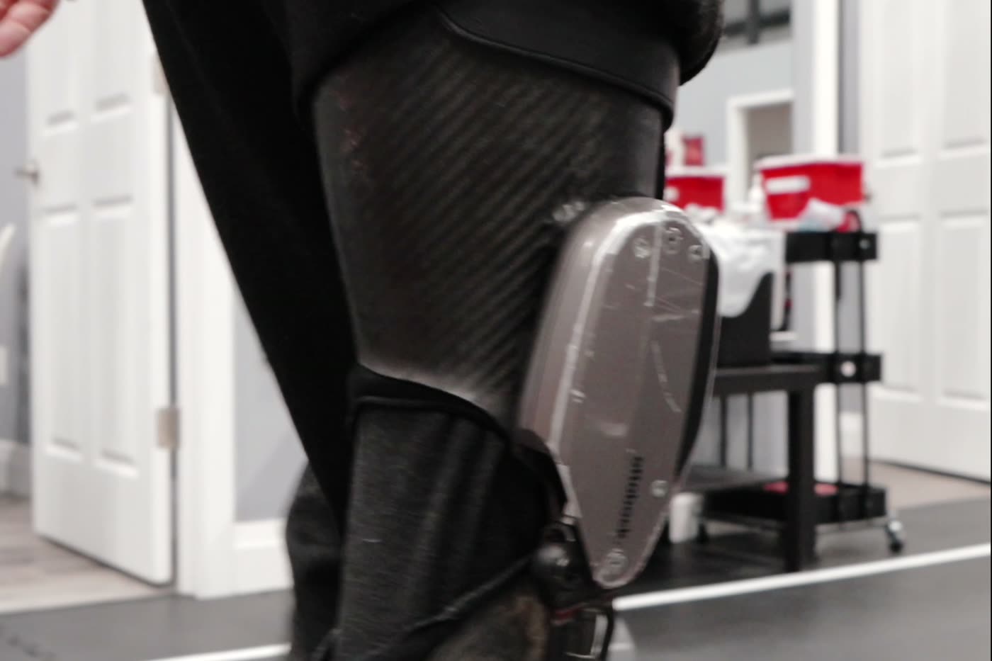 A client walking on the turf training lane with a leg brace at Bergin Motion